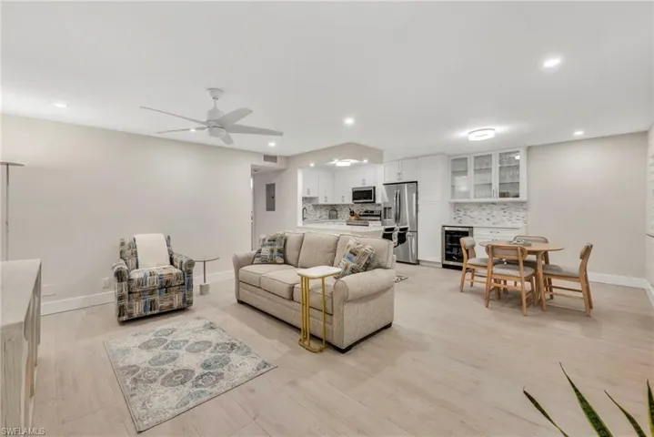 Living room featuring beverage cooler, light wood-style flooring, ceiling fan, and recessed lighting