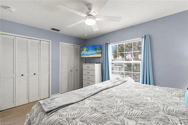 Carpeted bedroom with multiple closets, a  and ceiling fan