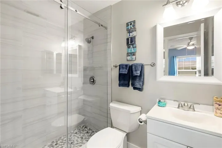 Full bathroom with vanity, a shower stall, and ceiling fan