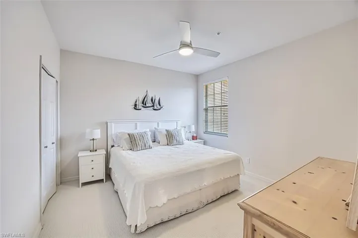 Bedroom with light colored carpet, a ceiling fan, and baseboards