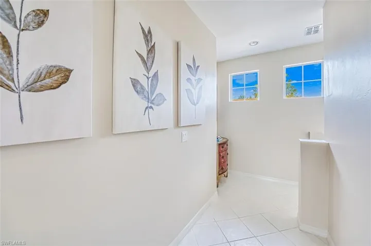 Corridor with visible vents, baseboards, and light tile patterned flooring
