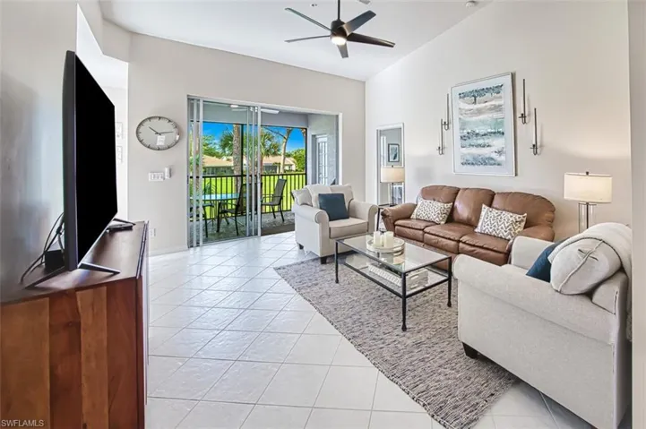 Living room featuring light tile patterned floors, ceiling fan, and vaulted ceiling