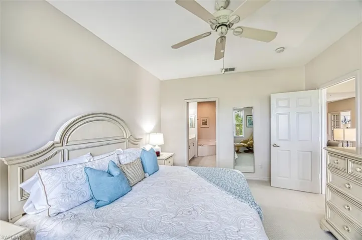 Bedroom featuring connected bathroom, light carpet, baseboards, and a ceiling fan