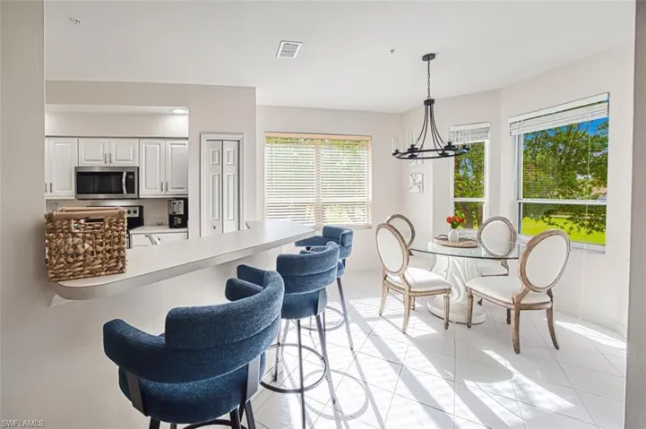 Dining space with light tile patterned floors, visible vents, and an inviting chandelier