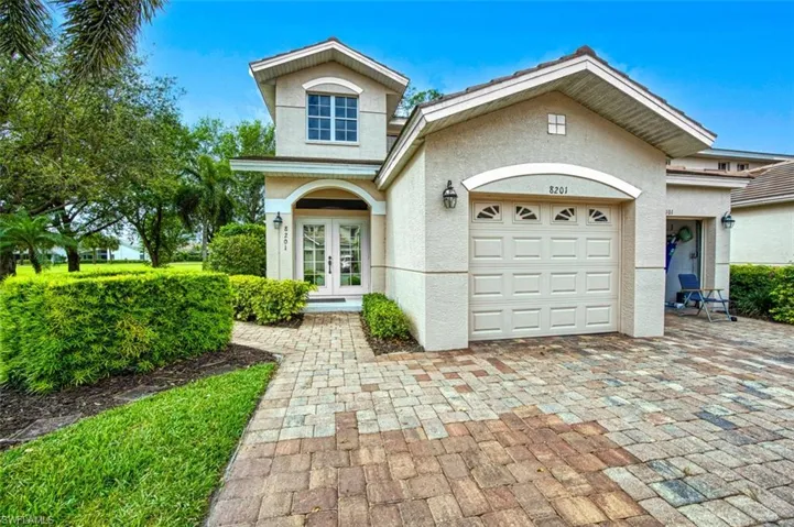 View of front facade featuring stucco siding, french doors, decorative driveway, and a garage