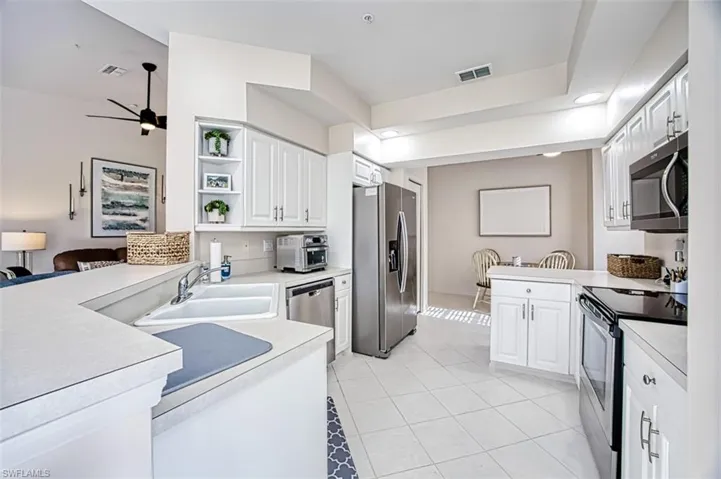 Kitchen featuring a sink, open shelves, white cabinetry, appliances with stainless steel finishes, and a peninsula