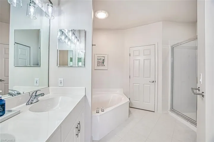 Bathroom with a shower stall, a garden tub, vanity, and tile patterned floors