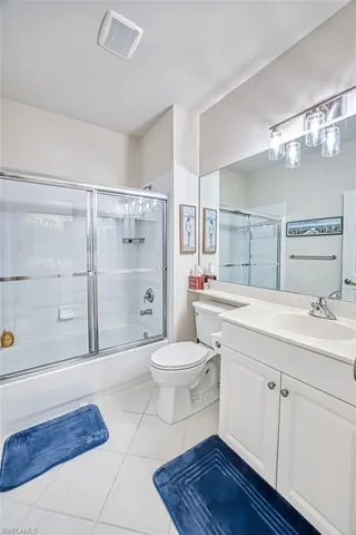 Full bathroom with tile patterned floors, visible vents, toilet, combined bath / shower with glass door, and vanity