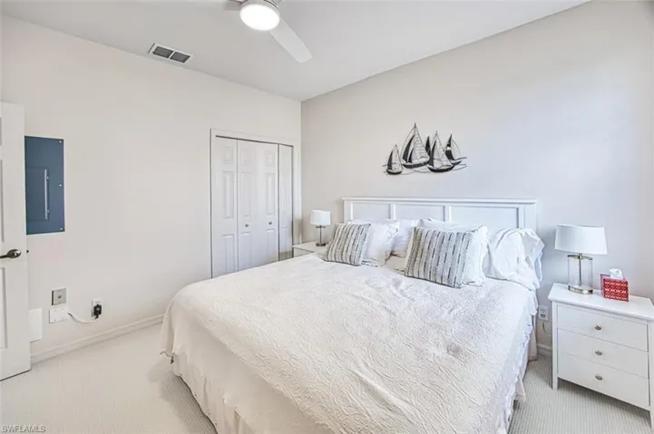 Bedroom featuring visible vents, ceiling fan, light colored carpet, electric panel, and a closet