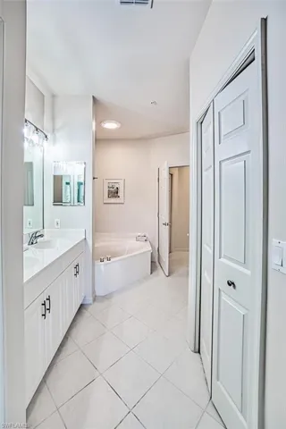 Bathroom featuring a sink, a bath, double vanity, and tile patterned flooring