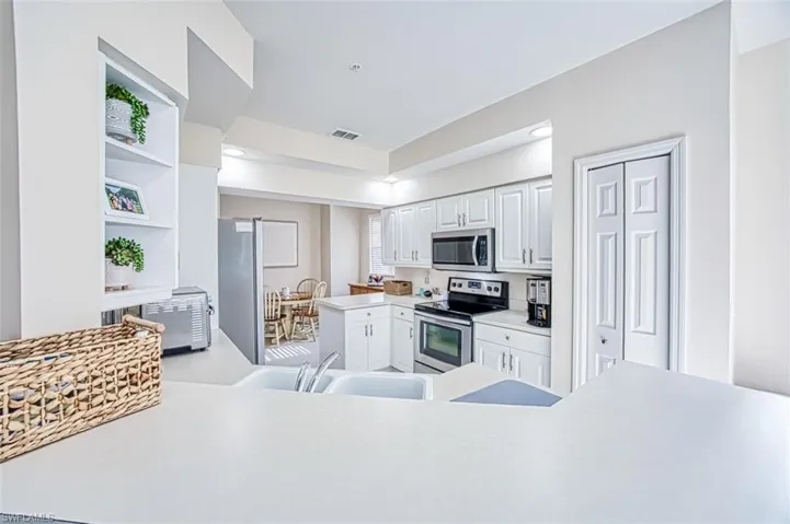 Kitchen featuring visible vents, light countertops, white cabinets, stainless steel appliances, and a sink