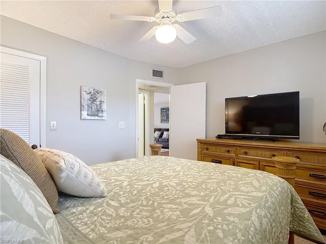 Bedroom with a textured ceiling and a ceiling fan