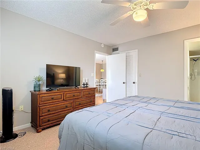 Bedroom with light colored carpet, baseboards, a textured ceiling, a ceiling fan, and a closet