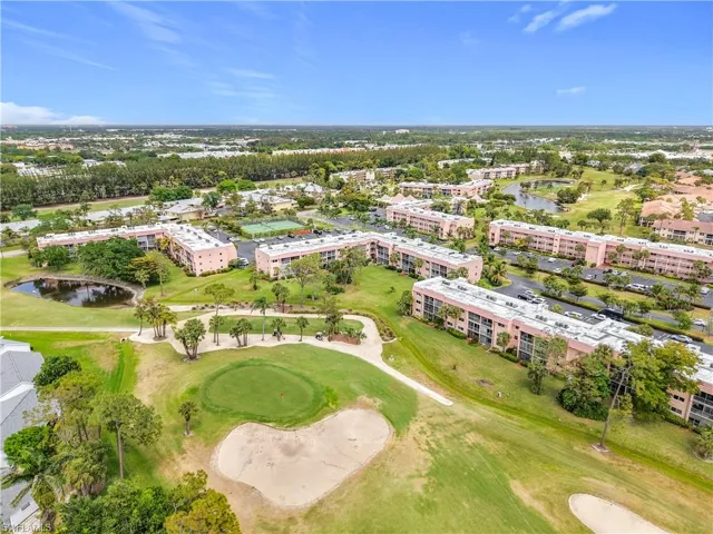 Drone / aerial view of apartment complex, a golf course, and a large body of water