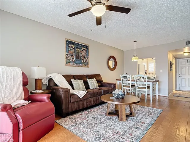 Living room featuring ceiling fan, a textured ceiling, and wood finished floors