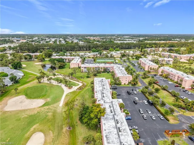 Drone / aerial view of apartment complex, a local golf course, and a large body of water