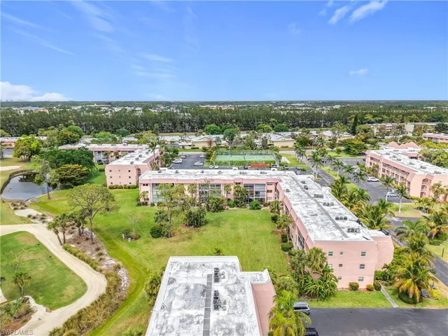 Bird's eye view of apartment complex, a tree filled landscape, and a nearby body of water