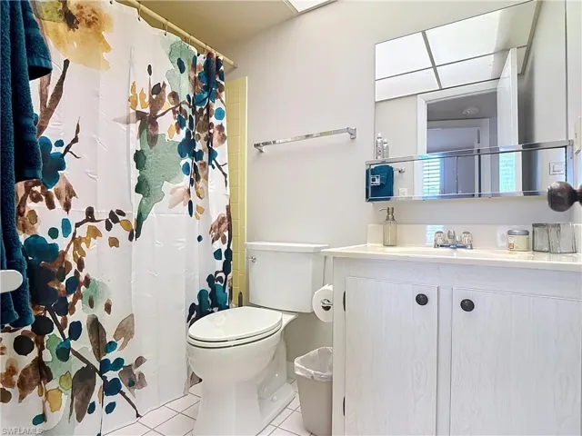 Full bath with tile patterned floors, toilet, vanity, and a shower with shower curtain