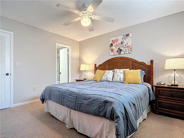 Carpeted bedroom with ceiling fan, a textured ceiling, and baseboards
