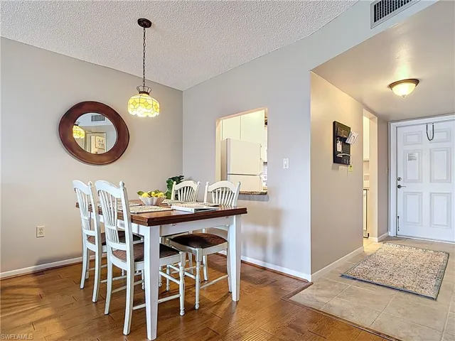 Dining area with a textured ceiling, wood finished floors, and baseboards