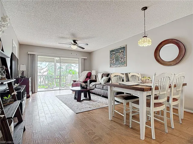 Living room featuring light wood-type flooring, ceiling fan, and a textured ceiling