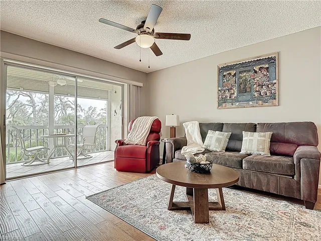 Living room featuring a ceiling fan, wood finished floors, and a textured ceiling