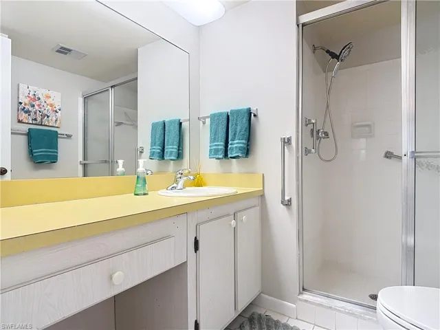 Bathroom with a shower stall, vanity, toilet, and tile patterned floors