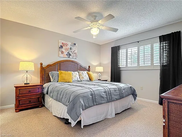 Bedroom with carpet flooring, a textured ceiling, baseboards, and a ceiling fan