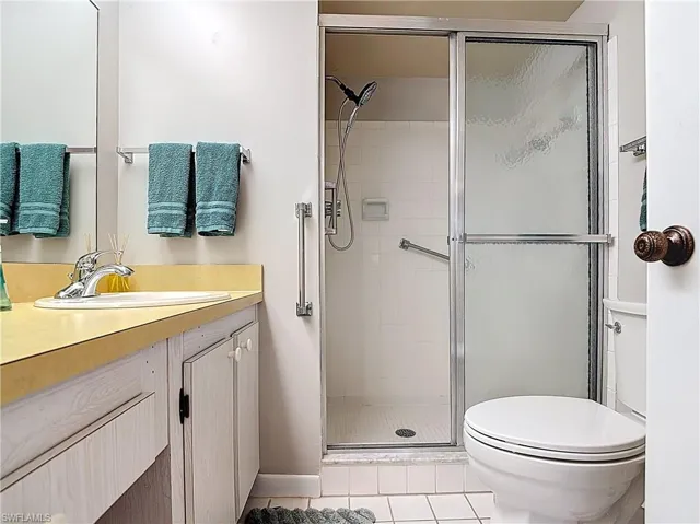 Full bathroom with toilet, a stall shower, tile patterned flooring, and vanity