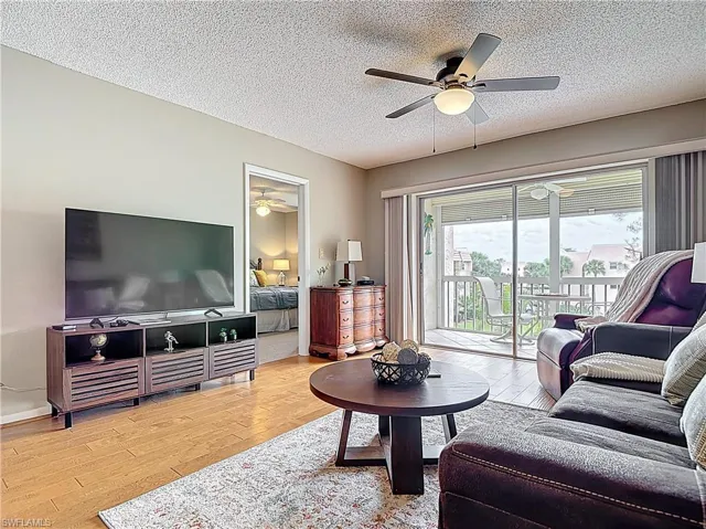 Living area with ceiling fan, wood finished floors, and a textured ceiling