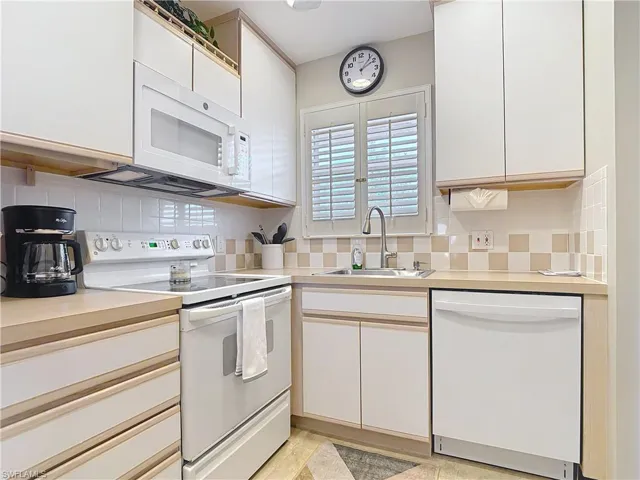 Kitchen featuring white appliances, a sink, and decorative backsplash