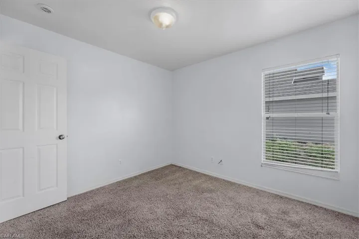 Neutral-toned wall-to-wall carpeting and bright white walls establish a versatile interior