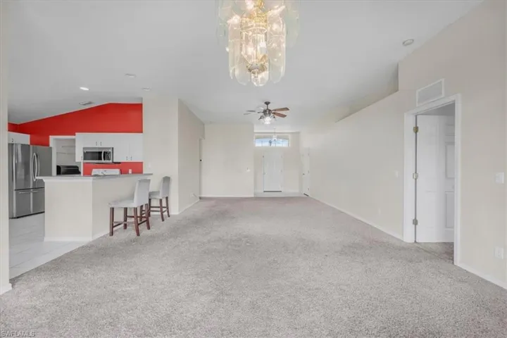 Open-concept living area featuring vaulted ceilings, recessed lighting, and a prominent decorative chandelier