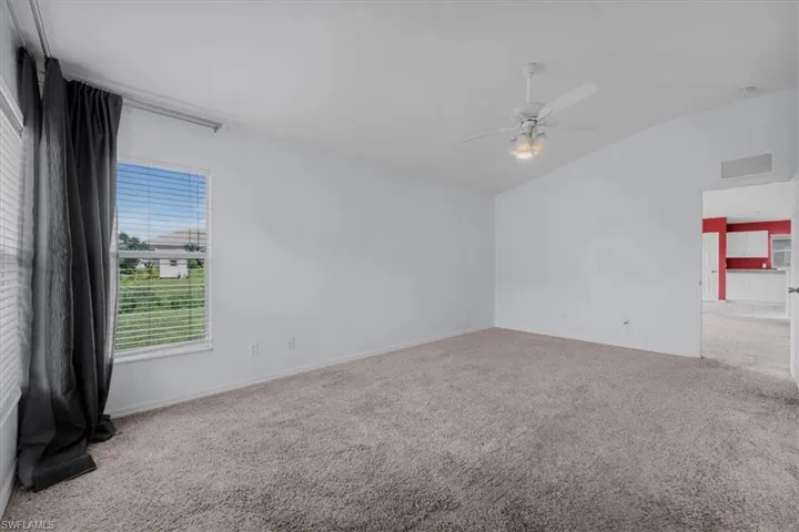 Spacious interior room featuring light gray carpeting and white painted walls