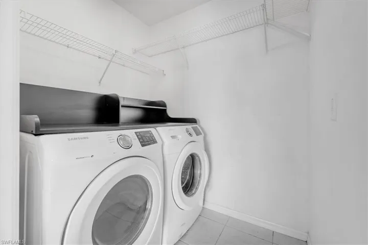 Dedicated laundry area featuring front-loading appliances, overhead wire shelving, and tiled flooring