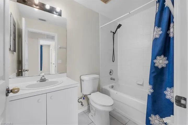 Bathroom featuring a single vanity with an integrated sink, white cabinetry, a rectangular mirror, and an overhead light fixture