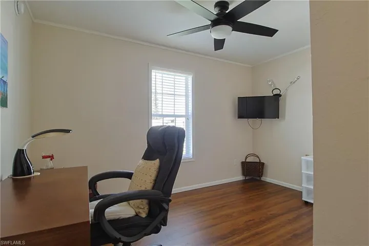 Office with dark wood finished floors, crown molding, and ceiling fan