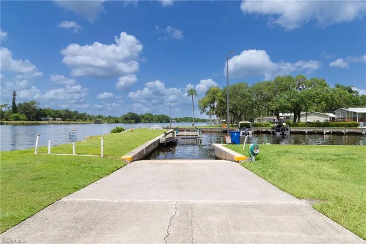 Dock area featuring a boat ramp, a water view, and a lawn