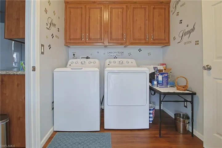 Laundry room featuring independent washer and dryer, dark wood-type flooring, and cabinet space