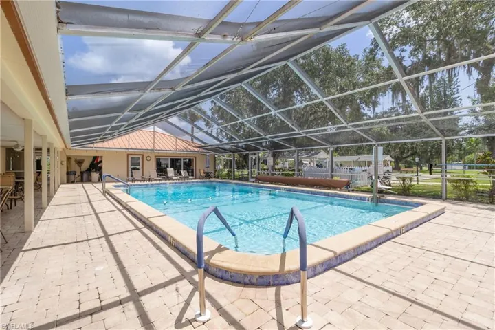 Community pool with a patio area, glass enclosure, and a sunroom