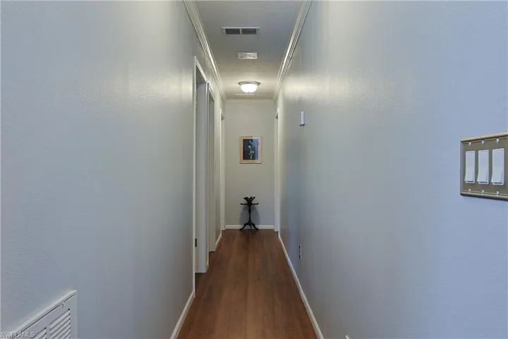 Hall with ornamental molding and dark wood-style flooring