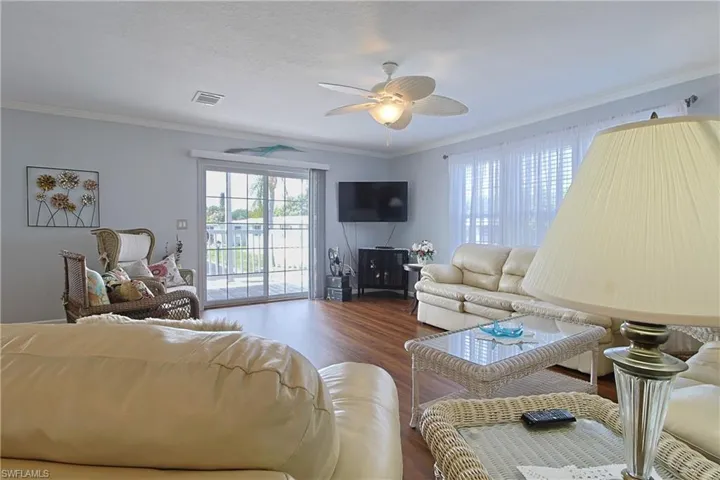 Living room featuring wood finished floors, crown molding, and a ceiling fan