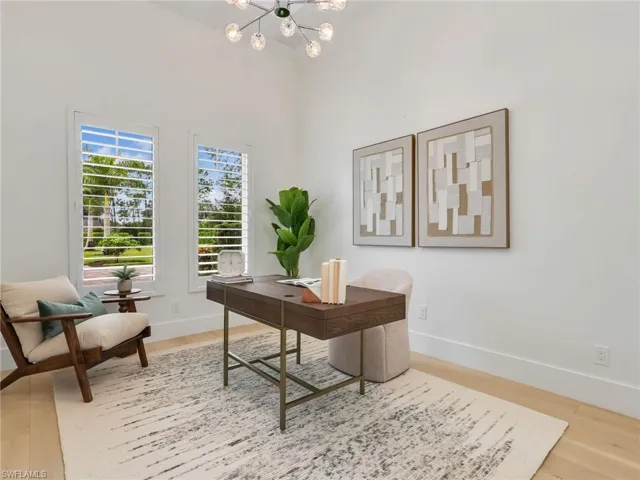 Vaulted ceilings with a contemporary chandelier, dual windows featuring plantation shutters, light wood-finish flooring, and a built-in desk