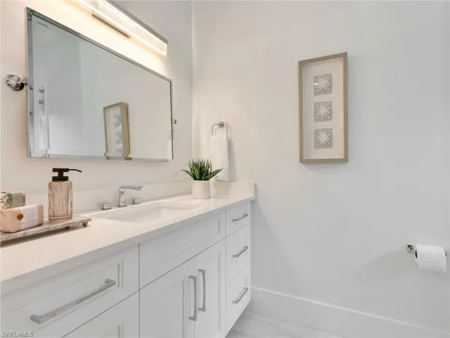 White vanity with shaker-style cabinetry, chrome hardware, and an undermount sink