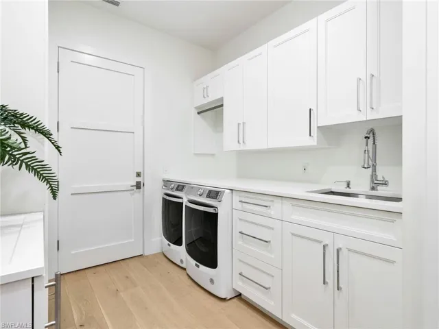 White shaker cabinetry with brushed nickel hardware, light wood-finish flooring, undermount sink with a gooseneck faucet, and white countertops