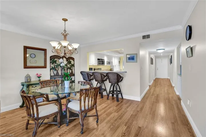Dining area with suspended lighting, light wood-type flooring, and crown molding