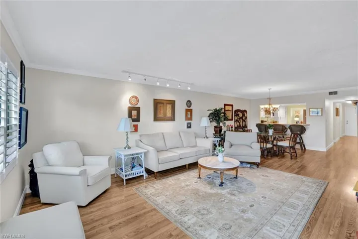 Living room featuring light wood-style floors, ornamental molding, and a chandelier