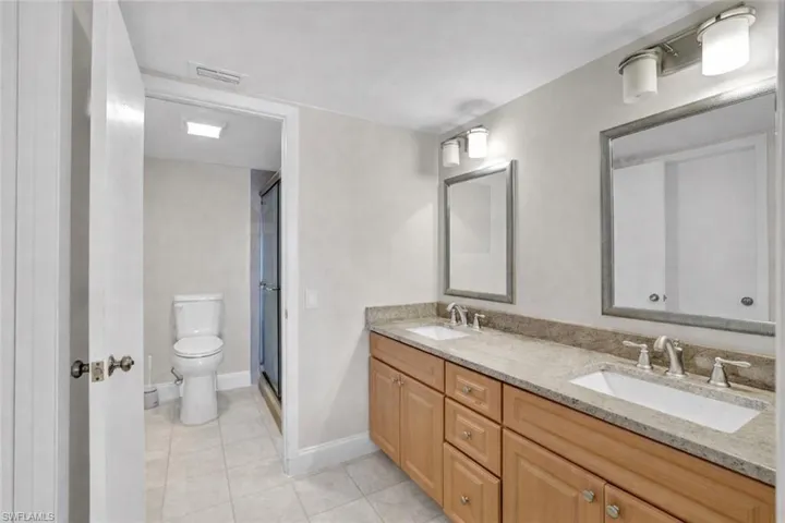 Bathroom featuring double vanity, a stall shower, and light tile patterned floors