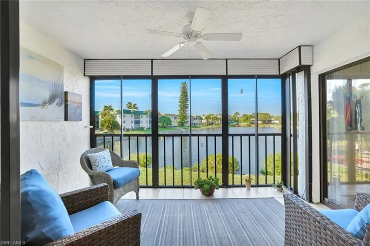 Sunroom / solarium with expansive windows, a textured ceiling, a water view, tile patterned flooring, and a textured wall