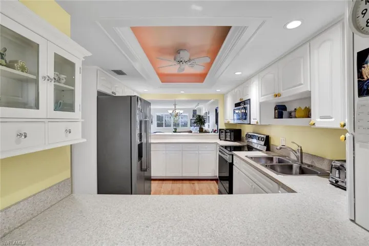 Kitchen featuring stainless steel appliances, white cabinetry, ceiling fan, crown molding, and light wood finished floors